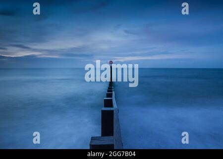 Effetto acqua dolce intorno ad un groyne di legno del mare a Southbourne Beach, Bournemouth. Scattata prima dell'alba, la scena assume i colori del Blue Hou. Foto Stock