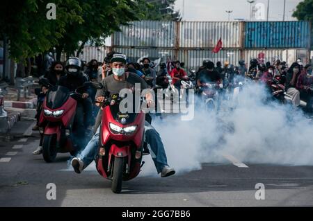 I dimostranti sono visti guidare le motociclette lontano dalla linea anteriore dopo che i poliziotti della sommossa hanno sparato i taniche del gas lacrimogeno durante la dimostrazione. Migliaia di manifestanti anti del governo hanno guidato i loro veicoli e hanno blare le corna in un convoglio 'Car Mob' chiedendo le dimissioni di Prayut Chan-o-Cha il primo ministro thailandese per il fallimento del governo nella gestione della crisi COVID-19. Una sera all'incrocio di DIN Daeng, centinaia di manifestanti anti anti-governativi provenienti da 'Car Mob' si sono riuniti all'incrocio di DIN Daeng e si sono scontrati con i poliziotti di sommosse. Foto Stock