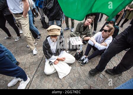 I manifestanti si siedono durante la dimostrazione. Più di mille persone si sono riunite per dimostrare in Piazza Dam, per dimostrare il loro sostegno alla recente situazione difficile degli afghani, ora in balia dei talebani. Il governo olandese ha designato l'Afghanistan come paese non sicuro, il che significa che i rifugiati hanno diritto alla protezione e all'asilo politico. La manifestazione odierna è stata organizzata da “Azadi”, un movimento di giovani afghani olandesi, ora parte di un movimento internazionale “eliminare gli afghani ora”. Il movimento ha organizzato 15 dimostrazioni attraverso l'Europa e le città americane. Dopo il rapporto di demonstrazione iniziale Foto Stock