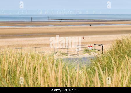 Tre dei cento Iron Men figurarono conosciuti come un altro luogo raffigurato sulla spiaggia di Crosby vicino a Liverpool nell'agosto 2021 visto sopra le dune di sabbia. Il Foto Stock