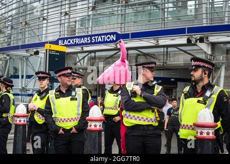 Linea di ufficiali di polizia alla marcia nazionale per i diritti degli animali, organizzata dalla ribellione animale e dalla ribellione di estinzione e un protestore con la mucca rosa papier-mâché, Londra, Inghilterra, Regno Unito. Agosto 28 2021 Foto Stock