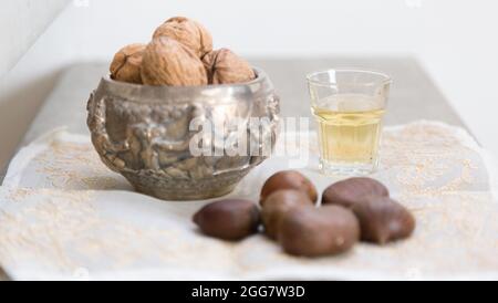 Noci, castagne e un bicchiere di liquore dorato su una superficie di cemento Foto Stock