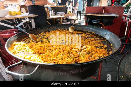 Una bancarella di Street food a Windsor, Regno Unito, che vende paella cotta in grandi padelle su bruciatori a gas. Foto Stock