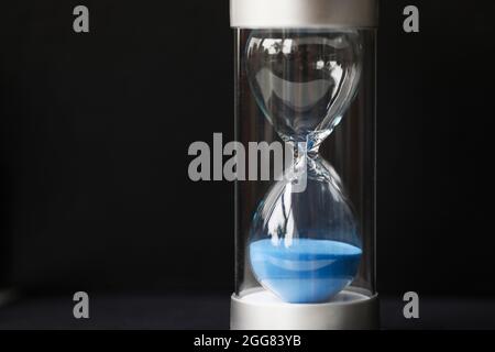 Elegante clessidra di vetro con sabbia blu da vicino Foto Stock
