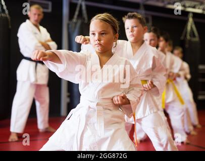 Ragazza che pratica nuove mosse durante la classe karate Foto Stock