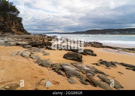 Putty Beach, Central Coast, NSW, Australia in una giornata di tempesta selvaggia con rocce in primo piano Foto Stock