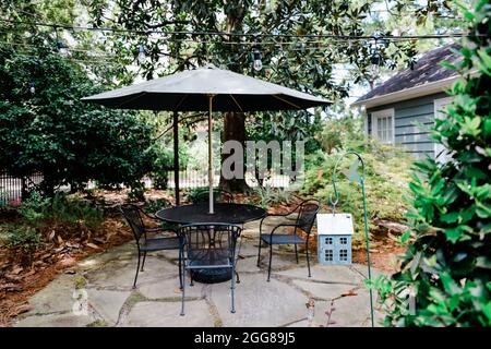 Cortile di una casa con un tavolo da patio e unbrella e alberi Foto Stock