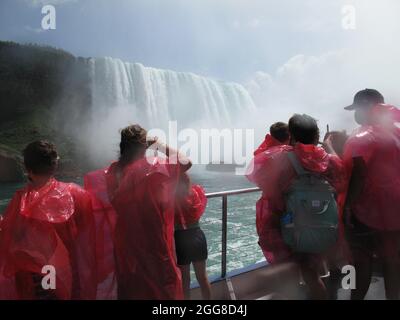 I turisti indossano impermeabili di plastica mentre osservano le cascate del Niagara Foto Stock