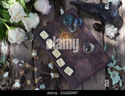 Grimoire magico con incantesimi, pentagramma, cristalli e rose sul tavolo delle streghe. Sfondo esoterico, gotico e occulto, concetto mistico di Halloween e wicca Foto Stock