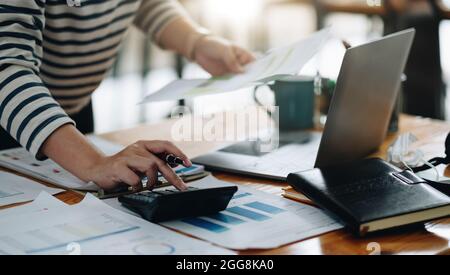 Primo piano contabile che lavora sulla scrivania utilizzando la calcolatrice per calcolare il report finanziario presso l'ufficio domestico Foto Stock