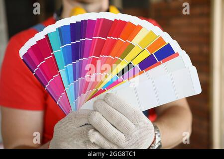 Un uomo in guanti mostra campioni di colore per la riparazione Foto Stock