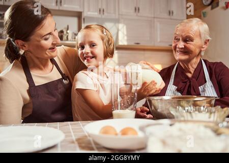 Ragazza giocosa che attacca la sua lingua mentre versa il latte Foto Stock