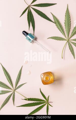 Cosmetica naturale. Concetto di Medicina alternativa a base di erbe. Cannabis viso siero o olio concetto contagocce e foglie di canapa su sfondo beige. Appartamento vista dall'alto l Foto Stock