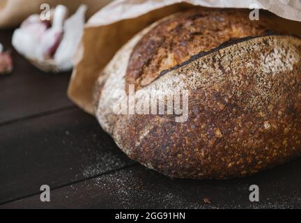 Primo piano pane caldo cerchio di segale su un tavolo di legno in confezione artigianale. Forno di pasta madre fatta in casa. Messa a fuoco selettiva. Foto Stock