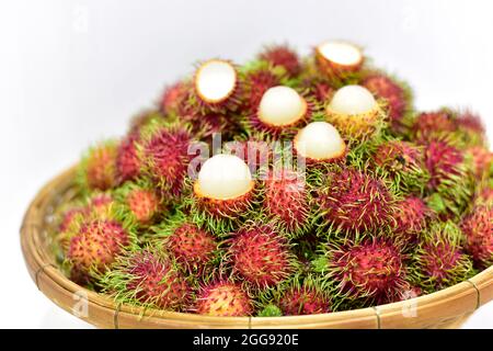 Rambutan, frutta tailandese in un cesto di bambù posto su sfondo bianco. Frutta fresca estate rambutan dal giardino in Thailandia. Fuoco selezionato Foto Stock