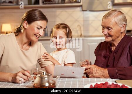 Famiglia allegra ammirando l'immagine della ragazza mentre beve il tè in cucina Foto Stock