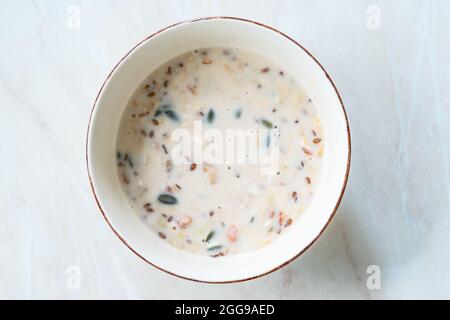 Produzione artigianale di Vegan senza glutine arrotolato avena con mirtilli, semi di zucca, mirtilli, fragole, semi di girasole e semi di lino in latte di mandorle calde per Foto Stock