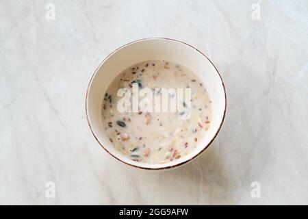 Produzione artigianale di Vegan senza glutine arrotolato avena con mirtilli, semi di zucca, mirtilli, fragole, semi di girasole e semi di lino in latte di mandorle calde per Foto Stock