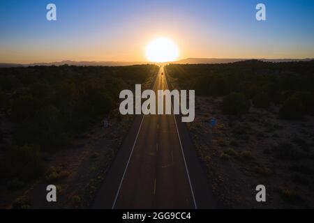 Lunga autostrada degli Stati Uniti che va dritto al tramonto all'orizzonte, Utah, Stati Uniti Foto Stock