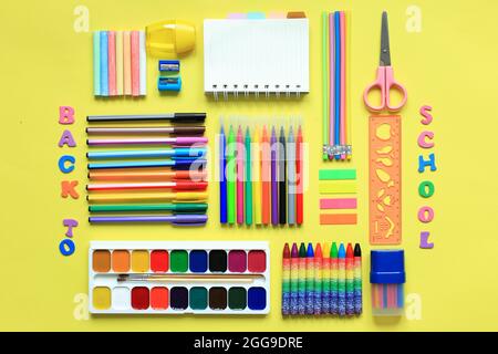 articoli per la scuola e l'ufficio, penne colorate, graffette, penne in  feltro, quadratini, un notebook vuoto per il proprio testo al centro Foto  stock - Alamy