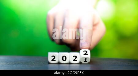 Mano gira un dado e cambia l'anno '2021' in '2022'. Foto Stock