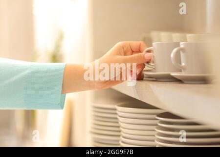 Primo piano di una donna che cova una tazza di caffè in cucina Foto Stock