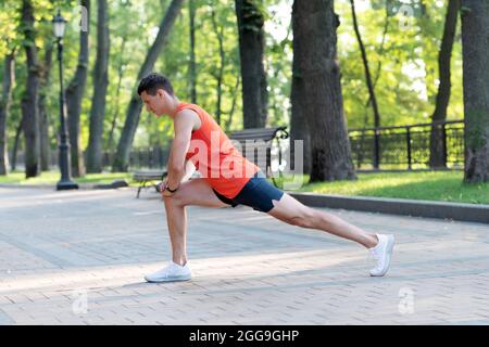 Posizione di affondo in posizione di mantenimento sportivo durante l'allenamento atletico all'aperto nel parco e nel riscaldamento Foto Stock