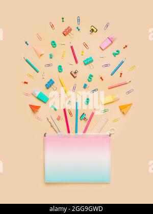 Scrivania creativa per studenti con forniture scolastiche e spazio per la copia sulla valigetta portadocumenti. Vista dall'alto o disposizione piatta. Trendy appartamento di ritorno a scuola su sfondo beige pastello neutro. Verticale Foto Stock