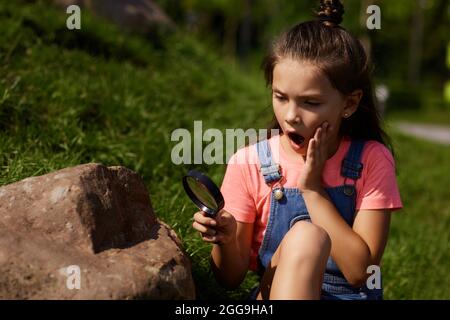 i capretti piccoli osservano hedgehog usando la lente di ingrandimento Foto Stock