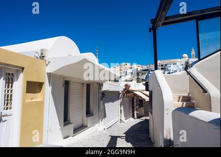 Strada stretta vuota a Thira, l'isola di Santorini. Negozi chiusi durante il rinchiuso del coronavirus. Architettura greca bianca/ Foto Stock