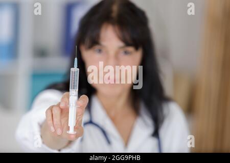 prima di effettuare l'iniezione, il medico maturo è stato glottato in una siringa contenente whitecoat Foto Stock