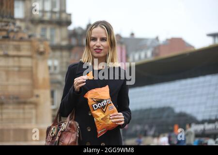 Glasgow, Scozia, ago 2021. Bella bionda giovane donna caucasica che mangia un pacchetto di Doritos in George Square, Glasgow. Foto Stock