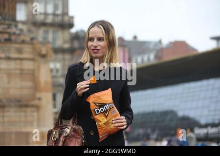 Glasgow, Scozia, ago 2021. Bella bionda giovane donna caucasica che mangia un pacchetto di Doritos in George Square, Glasgow. Foto Stock