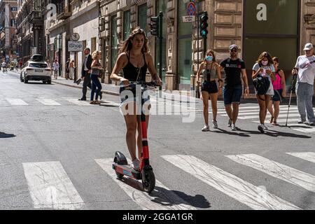 ROMA ITALIA, REGNO UNITO. 30 ago 2021. Donna che guida uno scooter elettrico in via del corso in una giornata calda a Roma. Gli scooter elettrici sono diventati popolari nella capitale romana e vengono utilizzati regolarmente come mezzi di trasporto per la mobilità. Credit: amer Ghazzal/Alamy Live News Foto Stock