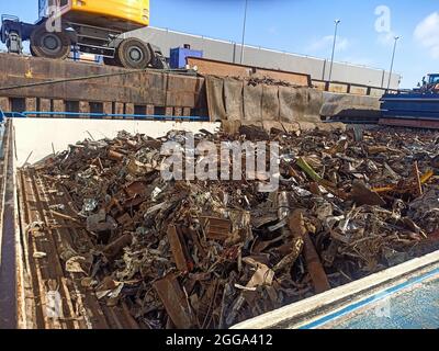 carico e scarico di rottami metallici nel porto sul molo dalla stiva della nave. Riutilizzo delle risorse. Esportazione di rifiuti metallici per il riciclaggio spedizione Foto Stock