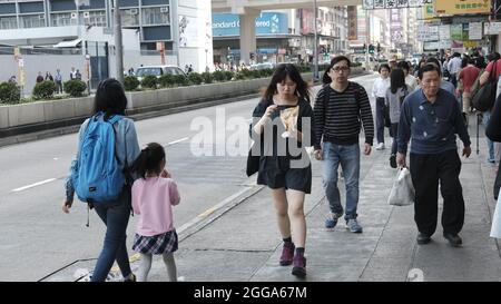 Young Lady pedonale mangiare snack Food Nathan Road è il passaggio principale a Yau ma Tai, Mongkok, Kowloon, Hong Kong, Cina Foto Stock