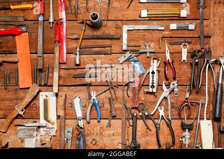 Interno di un'officina. Gli attrezzi sono appesi a una parete Foto Stock