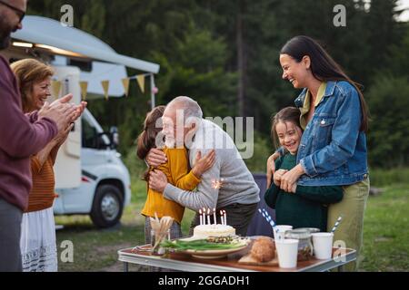 Multi-generazione famiglia festeggia compleanno all'aperto al campeggio, caravan viaggio di vacanza. Foto Stock