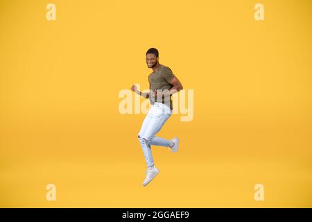 Gioia della vittoria. Eccitati afroamericani gesturing sì e saltare su sfondo giallo, spazio libero Foto Stock