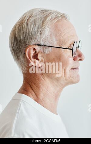Ritratto minimale della vista laterale di uomo anziano con capelli bianchi su sfondo bianco Foto Stock