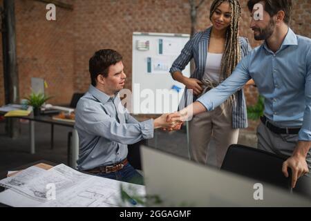 Down sindrome uomo scuotendo le mani con gli uomini d'affari in ufficio, inclusione sociale e concetto di cooperazione. Foto Stock