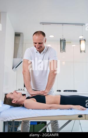 Felice donna allegra in nero sportswear sdraiato sul divano medico Foto Stock