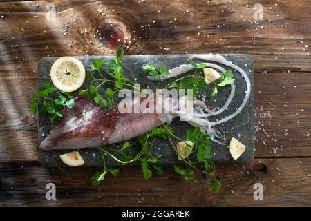 Presentazione di un calamaro fresco e crudo con prezzemolo e limone Foto Stock