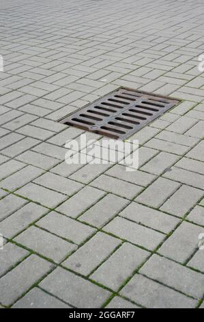 Colpo verticale di un tombino sul marciapiede con piastrelle di pietra Foto Stock