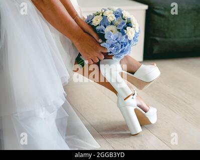 Sposa con bouquet in mani e sandali bianchi Foto Stock