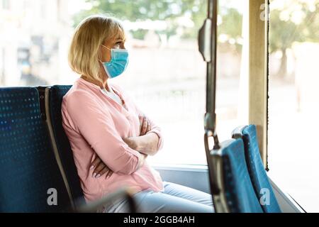 Donna matura messa a fuoco indossare maschera medica prendendo bus Foto Stock