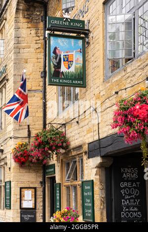 Bandiera britannica e un cartello che mostra un bugler e pubblicità Greene King birra sul Kings Arms pub e hotel a Stow on the Wold, il Cotswolds, Inghilterra Foto Stock