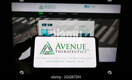 Persona che tiene il cellulare con il logo della società farmaceutica americana Avenue Therapeutics Inc sullo schermo di fronte al sito web. Mettere a fuoco sul display del telefono. Foto Stock