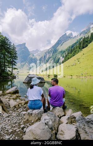 Lago di Seealpsee vicino ad Appenzell nelle Alpi svizzere, Ebenalp, Svizzera. Vista sulle montagne svizzere, coppia uomo e donna a mezza età in vacanza in Svizzera alpi con laghi e mucche Foto Stock