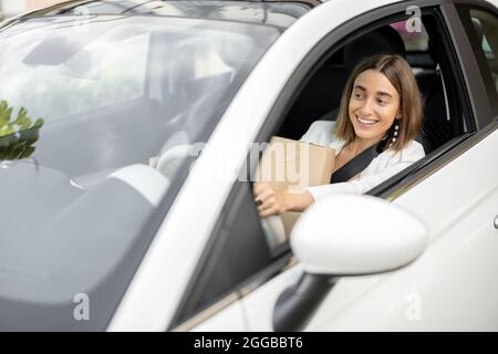 La donna guida un'auto con i pacchi nelle sue mani Foto Stock